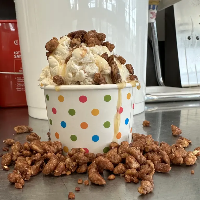 Ice cream sundae topped with candied walnuts spilling over the cup