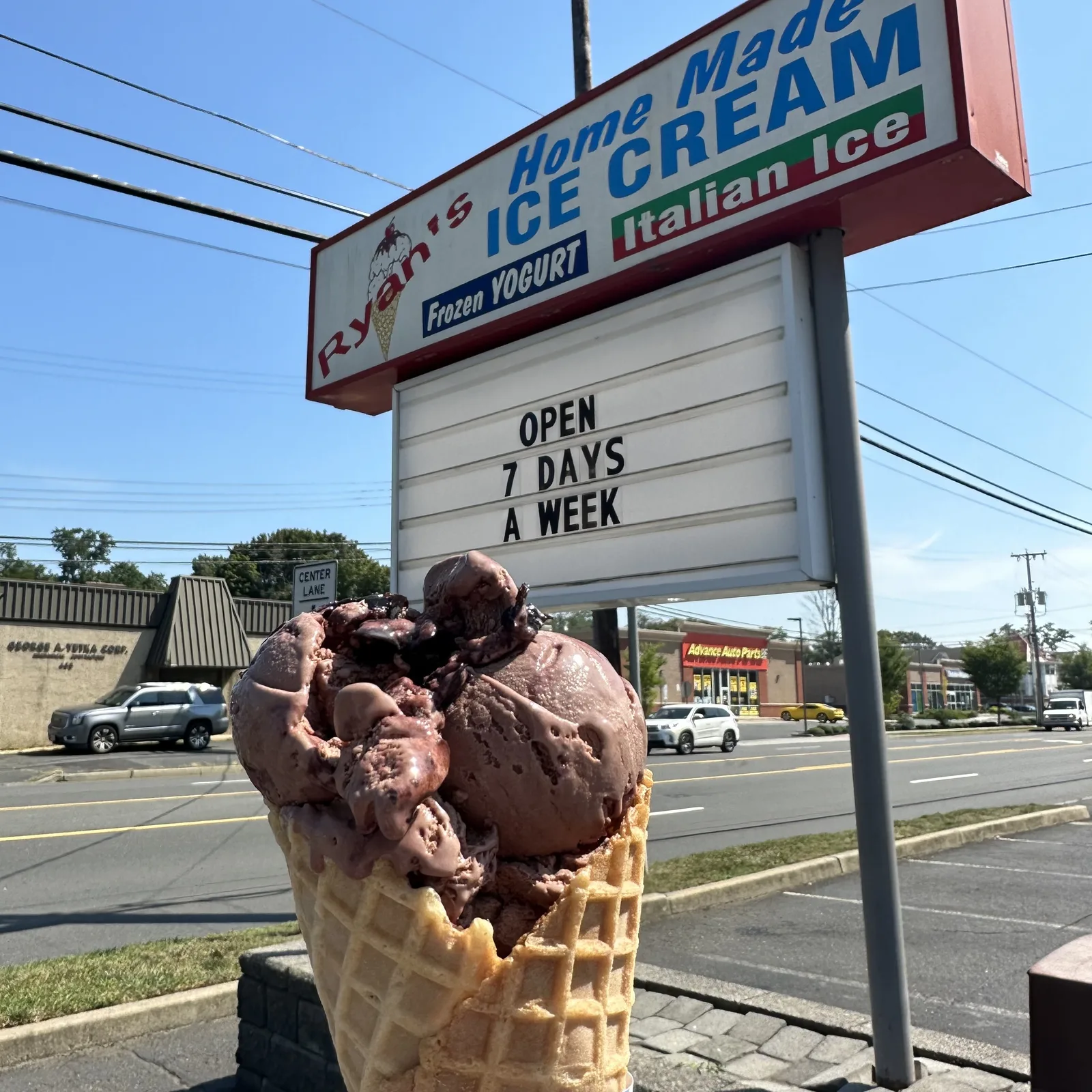Double scoop chocolate waffle cone in front of the Ryan's Homemade Ice Cream sign