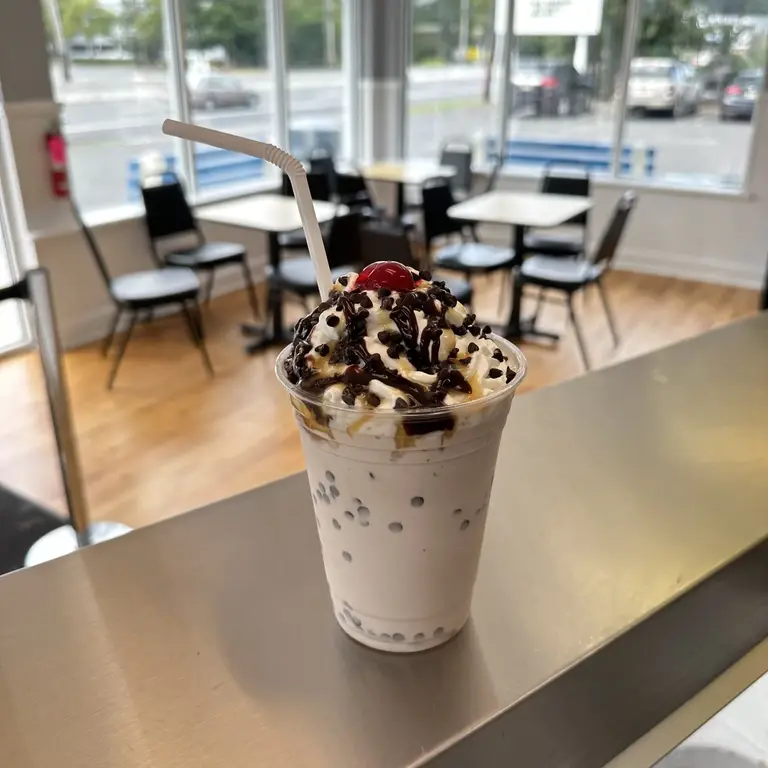 Hand-spun milkshake topped with whipped cream chocolate drizzle and a cherry