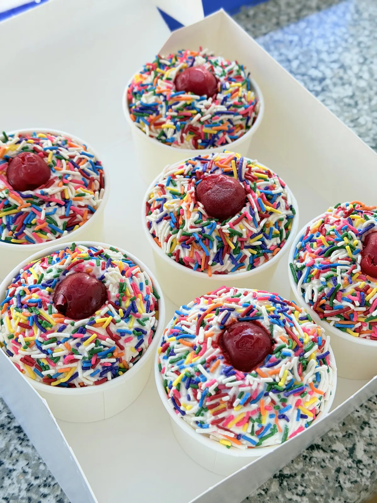 Mini ice cream party cups topped with sprinkles and cherries