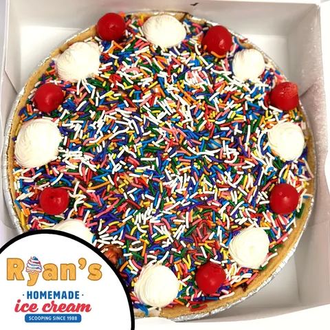 Ice cream pizza topped with cherries whipped cream and rainbow sprinkles