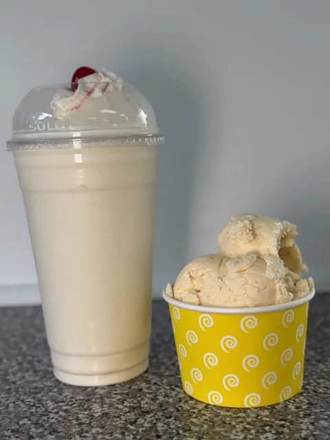 Hand-spun milkshake next to a cup of homemade ice cream