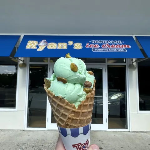 Mint chocolate chip waffle cone held in front of the Ryan's Homemade Ice Cream shop entrance