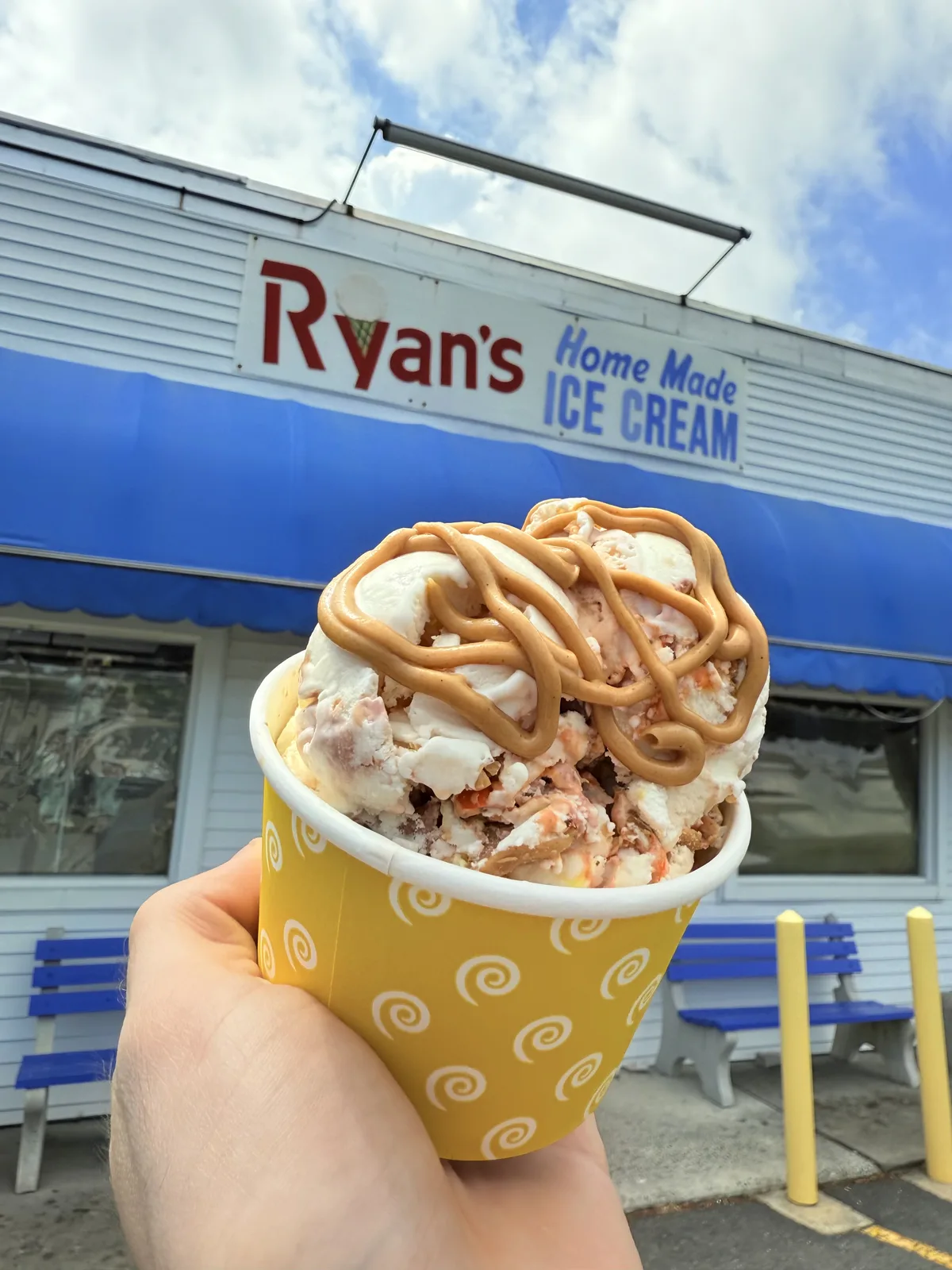 Ice cream topped with a thick peanut butter swirl in a yellow cup