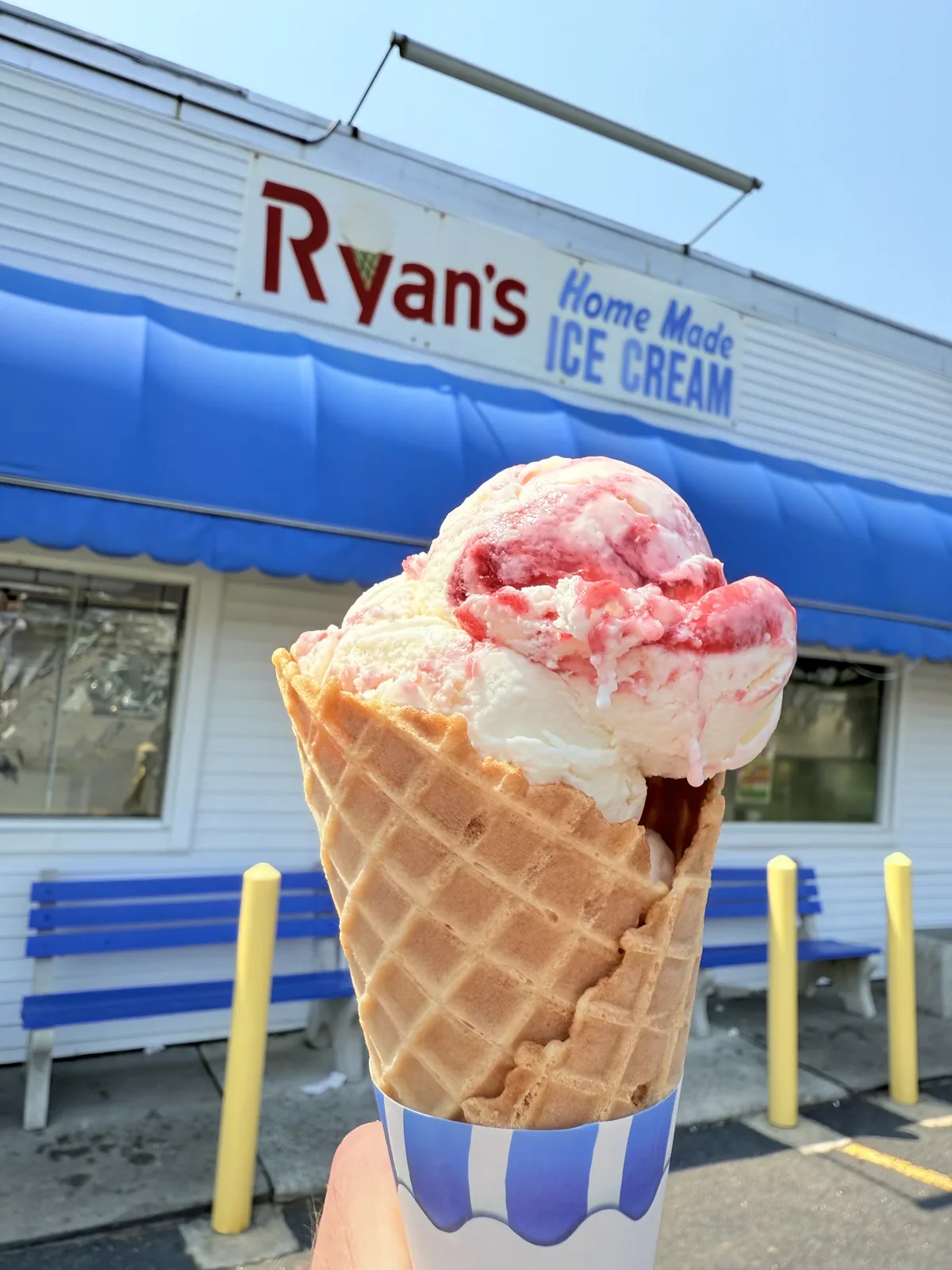 Raspberry cheesecake ice cream with red swirl on a tall waffle cone