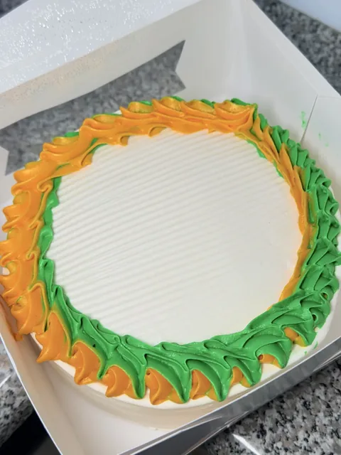 Round ice cream cake decorated with orange and green frosting