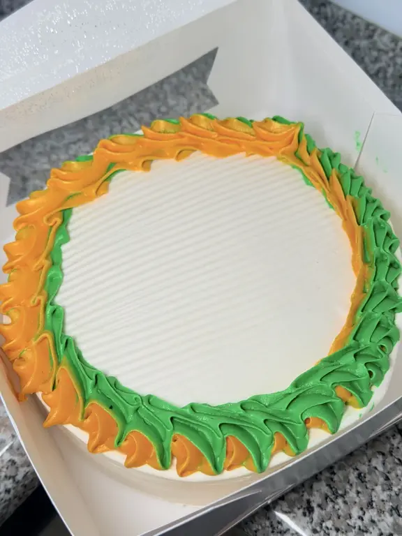 Round ice cream cake decorated with orange and green frosting